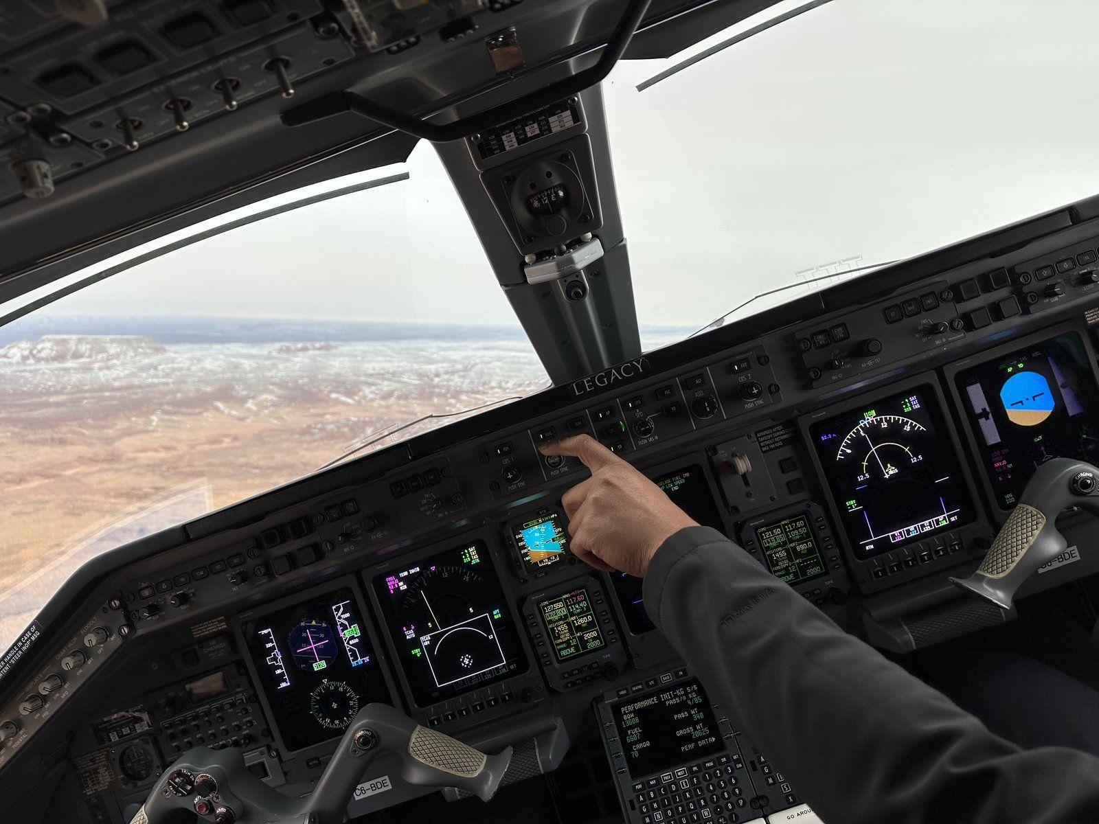 TIA pilot at the controls of a Legacy 600 in flight, monitoring avionics